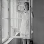 Schwarzweiß Bild einer Frau die Fenster putzt